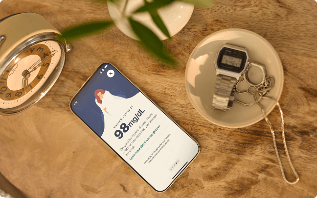 Phone with readings on table with clock and catch all dish containing watch and jewelry